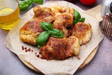 Tasty roasted chicken thighs with basil on grey table, closeup