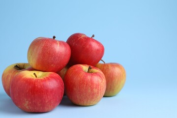 Ripe red apples on light blue background, closeup. Space for text