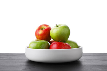 Red and green ripe apples in bowl on wooden table against white background