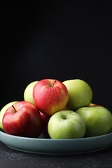 Fresh red and green apples on dark textured table against black background, closeup. Space for text
