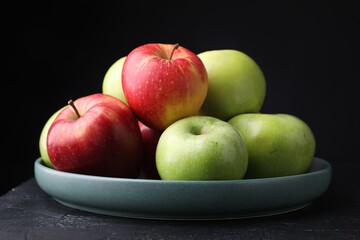 Fresh red and green apples on dark textured table against black background, closeup
