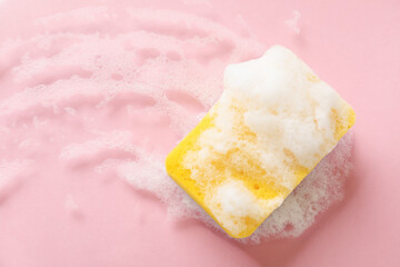 Kitchen sponge with foam on pink background, top view