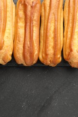 Tasty eclairs on black table, top view. Space for text