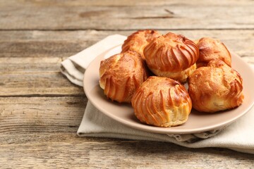 Tasty profiteroles on wooden table, closeup. Delicious dessert