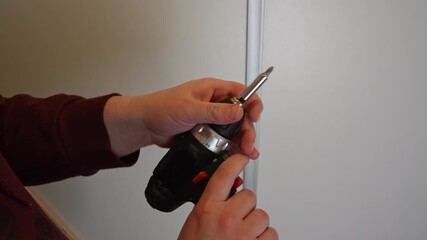 Hands inserting 12V rechargeable battery pack into cordless drill driver during tool preparation on light background. Concept of power tool assembly, battery installation and DIY equipment readiness