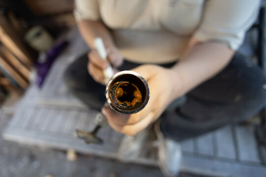 Plumber holding a cut section of an old metal water pipe, revealing severe rust and mineral buildup from corrosion inside, demonstrating the need for plumbing maintenance.