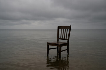 Naklejka premium A lonely wooden chair stands in the water by the sea.