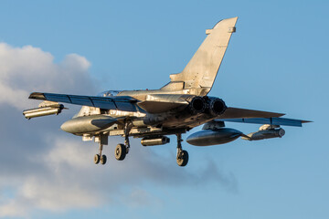 Vista trasera de caza de ataque aterrizando al anochecer