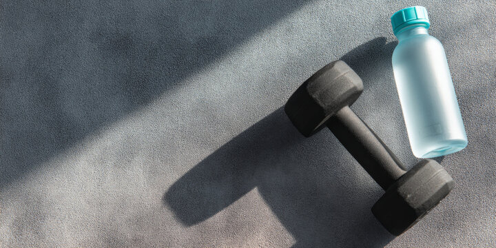 A dumbbell and a water bottle on the floor, suggesting exercise or fitness activities - Powered by Adobe