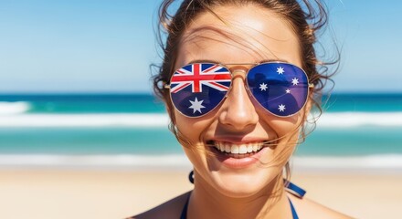 Young woman smiling on a sunny Australian beach wearing sunglasses with the Australian flag reflected for summer travel concept and national pride