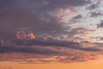 Scattered clouds of pinks, lavenders, blues, whites, setting sun below horizon line, yellow and orange gradient sky, tranquil, unblemished, naturalistic style