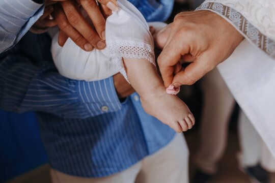 Priest anointing a baby's foot with holy oil using cotton during a baptism ceremony. Orthodox sacrament of Chrismation close-up