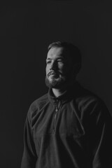 Black and white portrait of a young handsome man with a deep, introspective expression, highlighting emotion and character in natural light.
