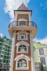 Brown and beige, old European city building with a unique architectural style Notable features include tall tower, multiple arched windows, balconies, pointed roof, and harmony with surroundings