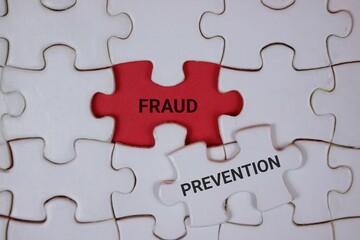 Fototapeta premium white puzzle pieces with an red center piece labeled FRAUD and an adjacent white piece reading PREVENTION, symbolizing awareness, detection, and proactive safeguards in business security.