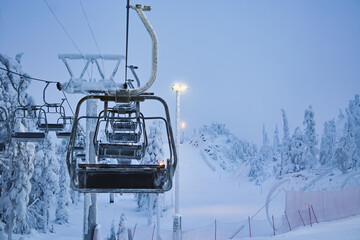 Frost-covered ski lift chairs on a quiet snowy slope at dawn. Winter landscape, ski resort...