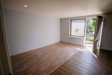 Bright, empty room with wooden flooring and large window, inviting natural light, showcasing minimalist design and open space for creative possibilities and interior decoration ideas