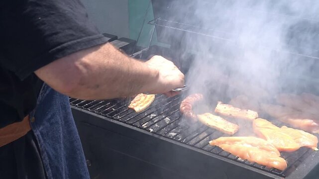 Man grilling meat on an outdoor barbecue. Leisure time with friends