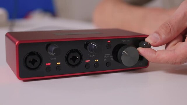 Adjusting external sound card knob, Precise control over audio output through knob rotation, Modifying sound levels using detailed textured dial on external audio interface