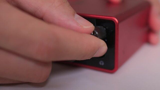 Adjusting external sound card knob, Precise control over audio output through knob rotation, Modifying sound levels using detailed textured dial on external audio interface