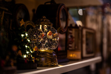 Illuminated snow globe with birds and glitter inside on a shelf, wonder and cozy decoration for Christmas.