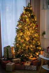 Decorated Christmas tree with glowing lights and gift box under it in living room.