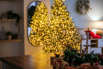 Warm Christmas setting with decorated table, wrapped gifts, and blurry festive lights. Cozy holiday background