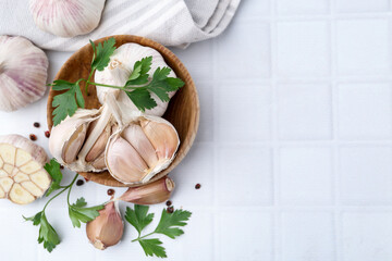 Garlic, peppercorns and parsley on white table, flat lay. Space for text