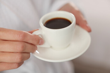 Woman in bathrobe with morning coffee indoors, closeup