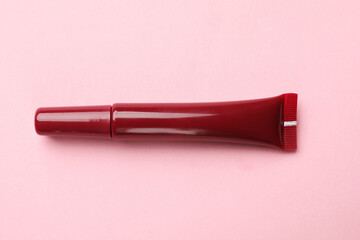 Beautiful dark red lip gloss on pink background, top view