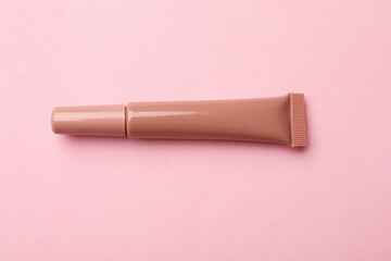 Beautiful nude lip gloss on pink background, top view