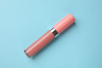 Beautiful lip gloss on light blue background, top view