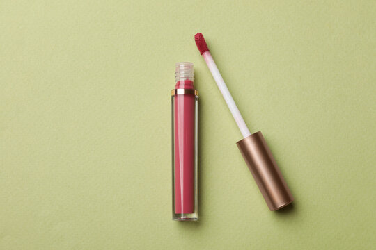 Beautiful pink lip gloss on light green background, top view