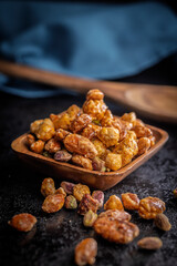 Nuts coated in sugar glaze in bowl on black table.