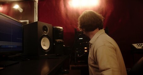 Music producer listening to audio track in professional recording studio