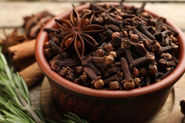 Mulled wine spices. Cloves, anise star in bowl and fresh rosemary on table, closeup