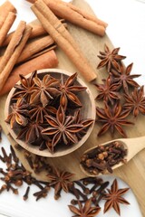 Mulled wine spices. Anise stars in bowl, cinnamon sticks and cloves on white table, flat lay