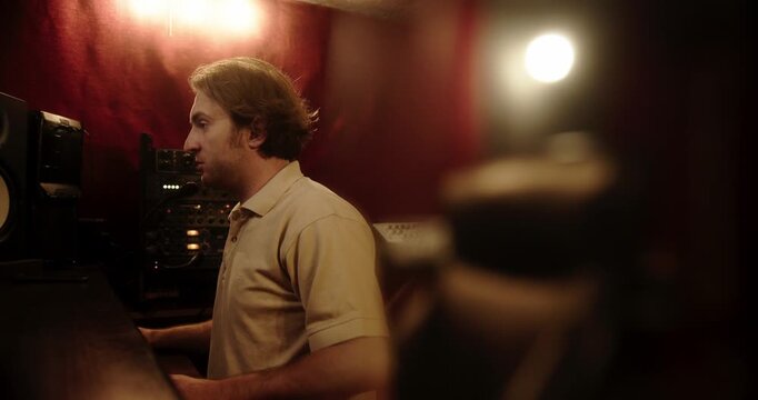 Music producer speaking on a talkback microphone in a recording studio