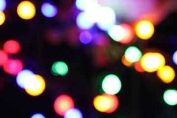 Fototapeta premium Blurred view of bright Christmas lights on dark background, bokeh effect