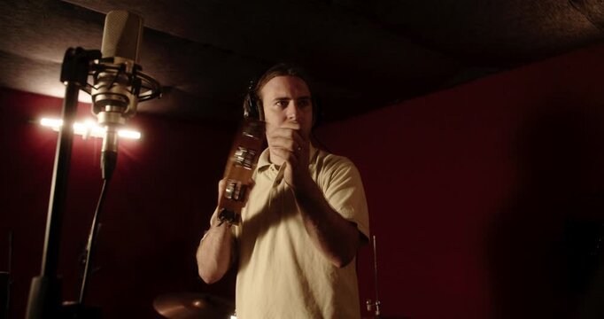 Male musician playing tambourine in professional recording studio