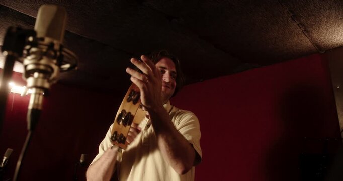 Professional musician playing tambourine in recording studio