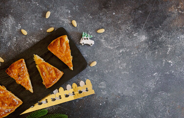 Four fresh pieces of crown galette, a toy and an almond on the table.