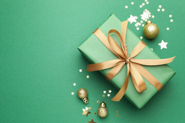 Beautiful Christmas composition with gift and decor on green background, flat lay. Space for text