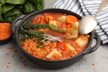 Tasty lentil soup served on grey table, closeup