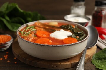 Tasty lentil soup served on wooden table, closeup