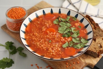 Tasty lentil soup in bowl served on light table, closeup