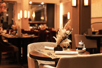 Elegant, reserved table in a dimly lit luxury restaurant with a dried floral centerpiece, set for fine dining.