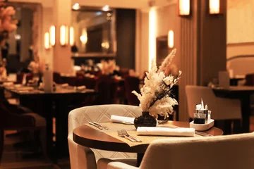 Fotobehang Hotel chique Elegant, reserved table in a dimly lit luxury restaurant with a dried floral centerpiece, set for fine dining.  © Kyrylo