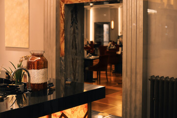 Restaurant interior with a decorative jar of beans on a sleek counter, framed by an entrance to the dining room.