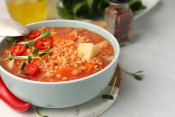 Delicious lentil soup with vegetables served on light grey table, closeup. Space for text